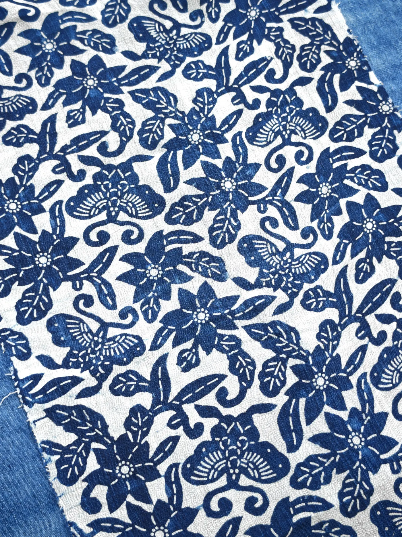 Blue-and-white butterfly and floral repeat on an open woven summer cloth.