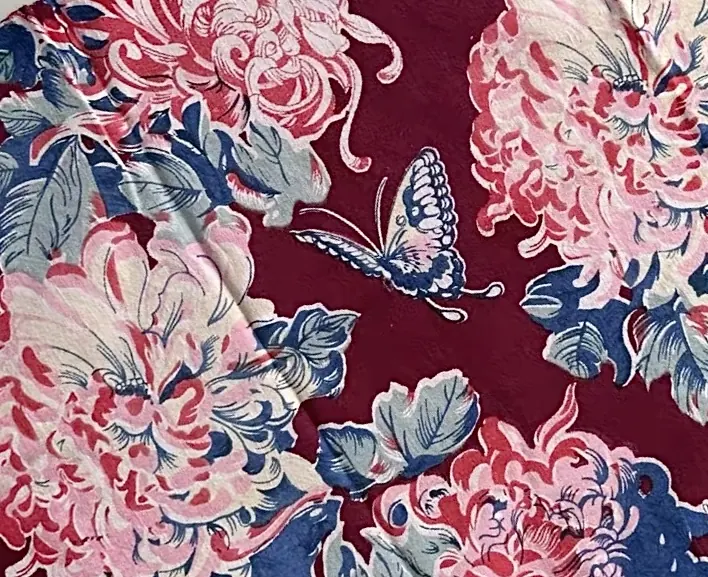 Naturalistic butterfly among pale pink flower clusters on a burgundy ground.