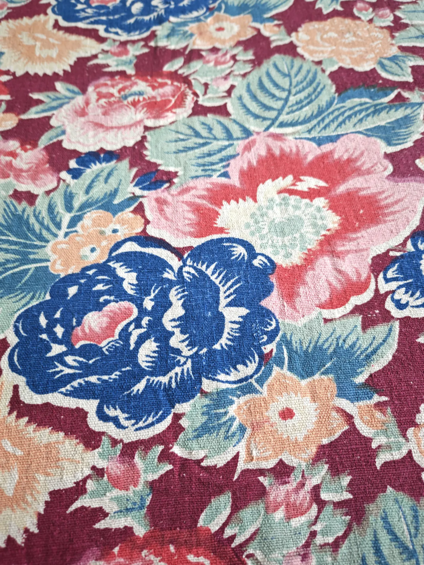 Dense multicolour peony garden on a wine-red handwoven cotton ground.