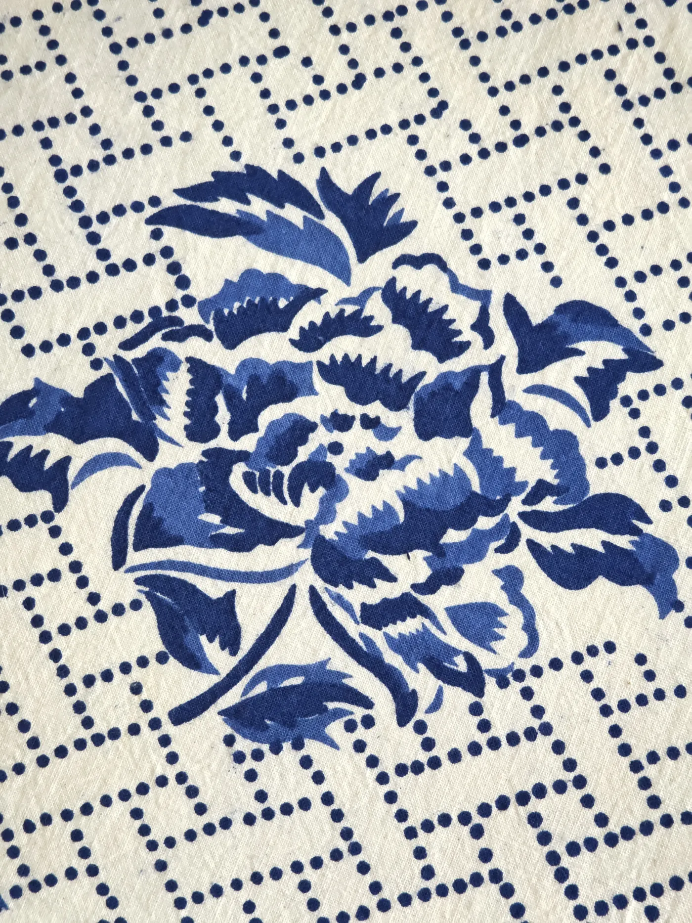 Blue peony printed over an ivory ground with a dotted geometric lattice.