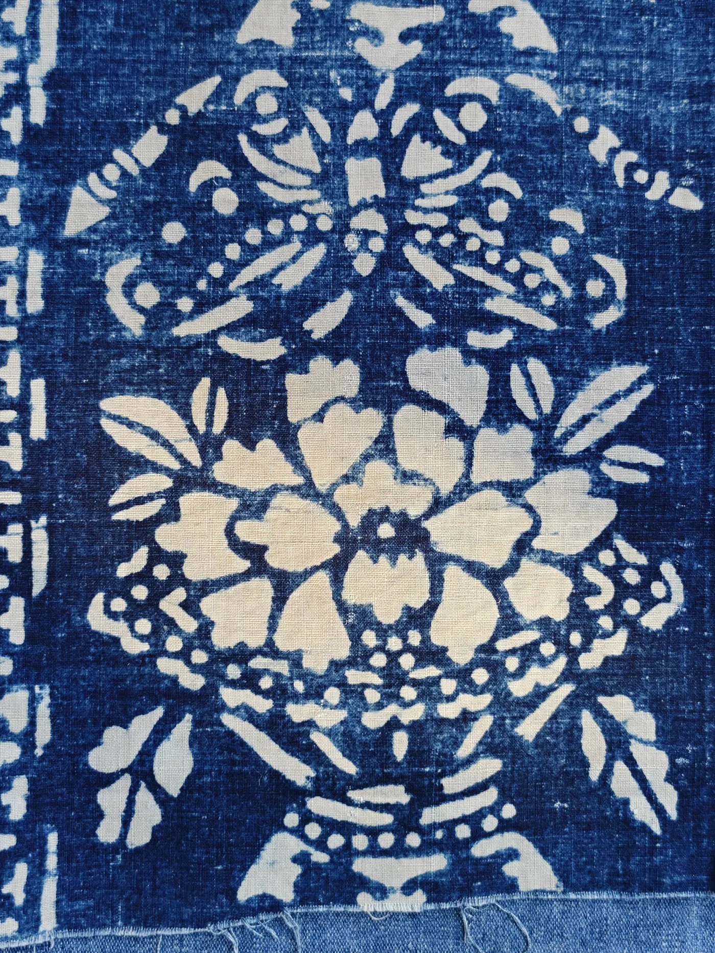 Indigo-style blue floral composition with a large peony-like flower in a vessel or basket arrangement.