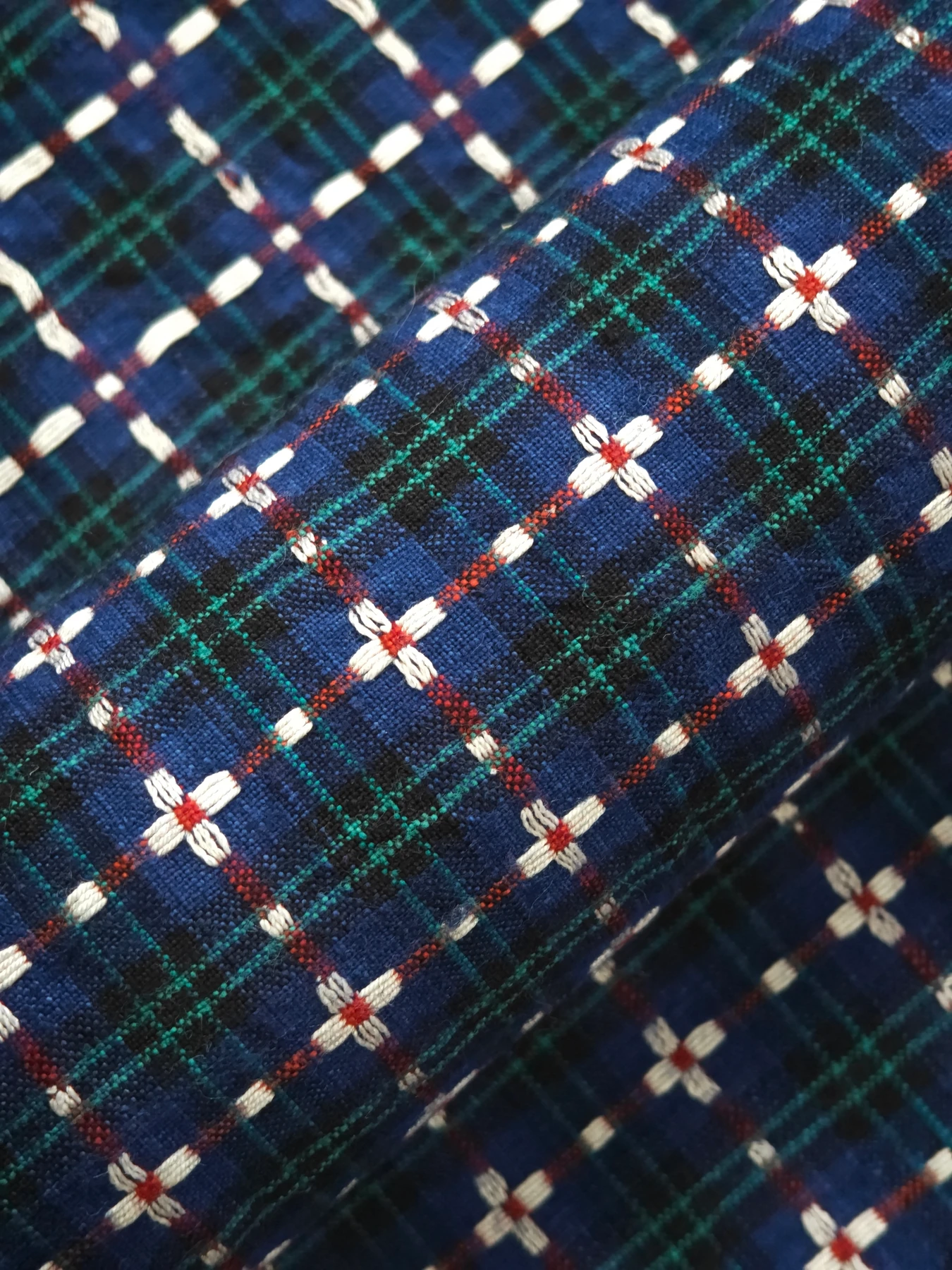 White four-petal flowers with red centres on folded blue, green and red checked Shanghai homespun.